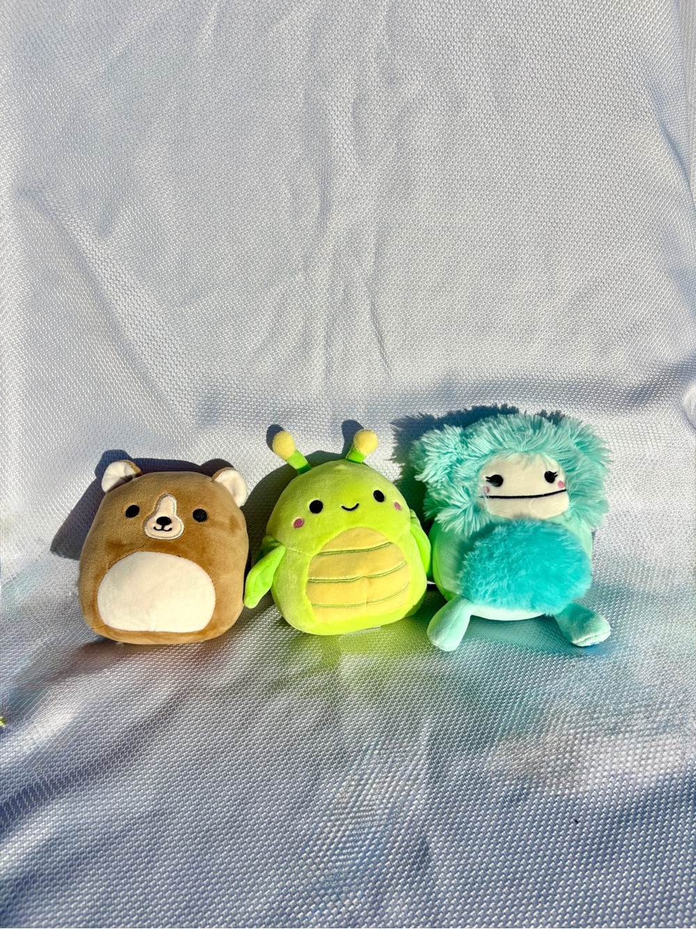 Squishmallows brown Bear, teal Bigfoot, and green grasshopper